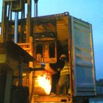 Forklift handling industrial cargo inside a shipping container during an evening operation