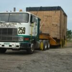 Tractor head hauling a crated generator unit on a low-bed trailer