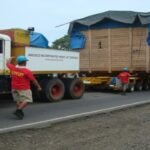 Heavy transport convoy hauling a large crated generator on a multi-axle trailer