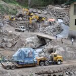 Tractor head hauling covered heavy industrial equipment toward a powerhouse construction site