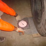 Transport crew measuring the wheel load of a heavy cargo trailer using a portable scale
