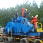 Rigging crew attaching lifting slings to heavy industrial equipment on a modular trailer