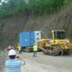 Crawler bulldozer assisting the transport of large industrial equipment along a narrow mountain access road