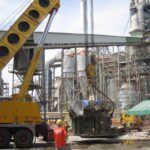 Mobile crane lifting heavy industrial equipment at a processing facility