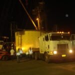 Heavy transport crew handling oversized mining equipment during a nighttime operation