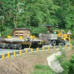 Modular multi-axle trailer transporting heavy equipment along a curved road