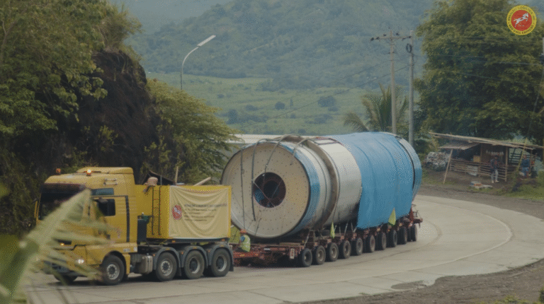 Oversized cylindrical project cargo transported on a multi-axle trailer along a curved roadway