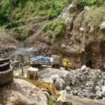 Truck hauling heavy industrial equipment through a steep and rocky construction access route