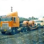 Tractor head hauling steel sheet rolls along an unpaved access road